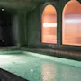 Rauhallinen sisäuima-allasalue porealtaalla ja lämpimästi hehkuvilla kaarevilla ikkunoilla, kutsuen rentoutumaan ja rauhoittumaan.