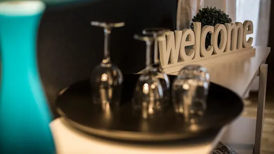 Wine glasses and a decorative 'welcome' sign on a table, with soft focus.