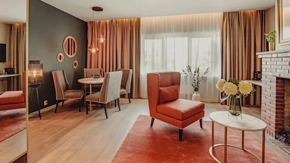 Elegant living room with cohesive warm color scheme, featuring furniture and decorations, well-lit by natural light from windows.