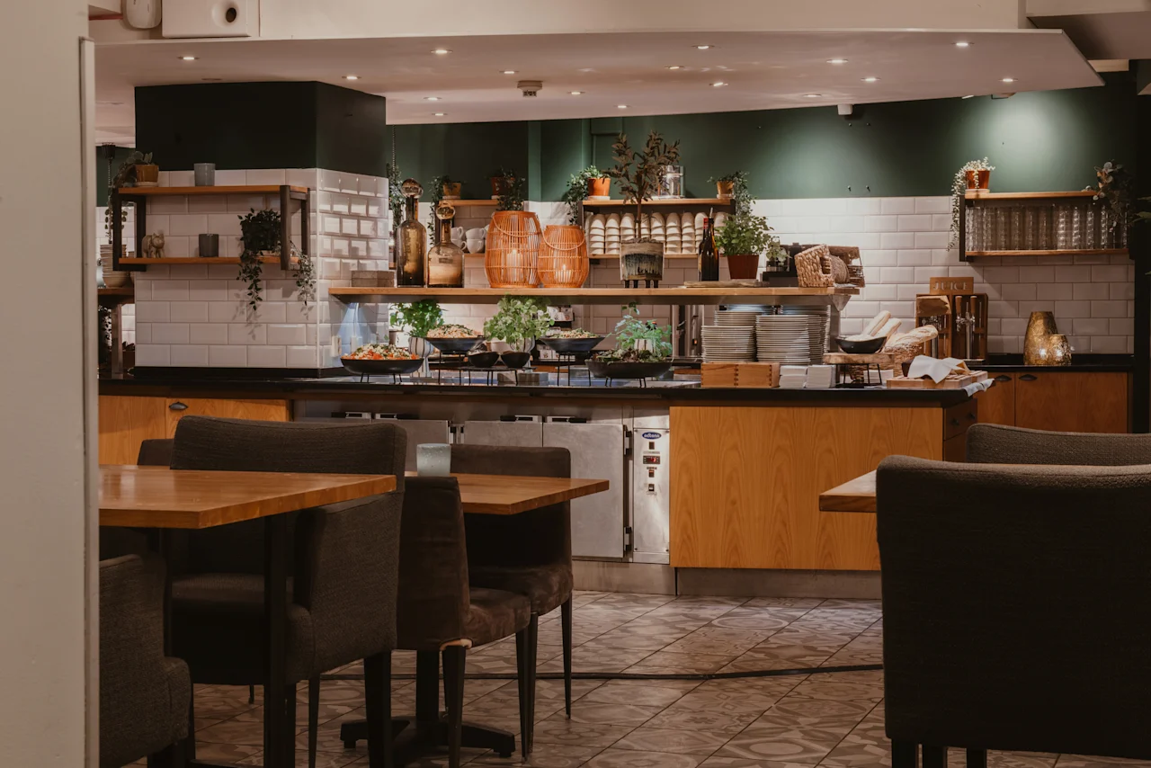 En inbjudande bufféavdelning på Home Hotel Grand, Helsingborg, med färsk mat, prydligt staplade tallrikar och mysig inredning.