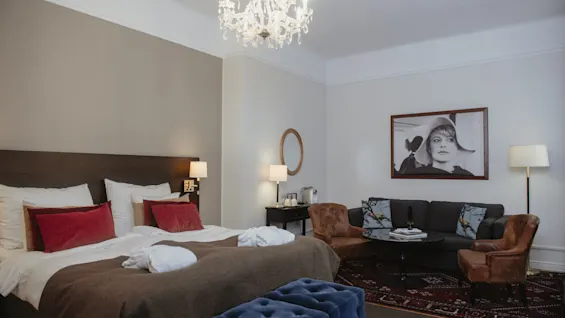 Ylellinen hotellihuone, jossa on suuri sänky, mukava oleskelualue ja tyylikäs sisustus, täydellinen rentoutumiseen.