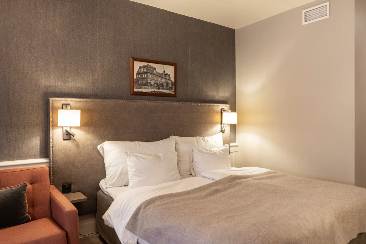A comfortable and inviting hotel room at Home Hotel Grand Bodø, featuring a large bed with soft linens and warm lighting.
