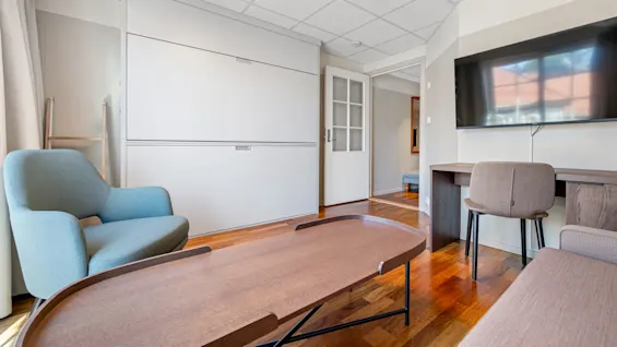A modern conference room with a large table, chairs, a screen, and a whiteboard set in a brightly lit interior.