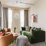 Et stilfuldt hotelsuite-opholdsrum på Hernö Gin Hotel, med en komfortabel grøn sofa, lænestole og et tilstødende soveværelse.