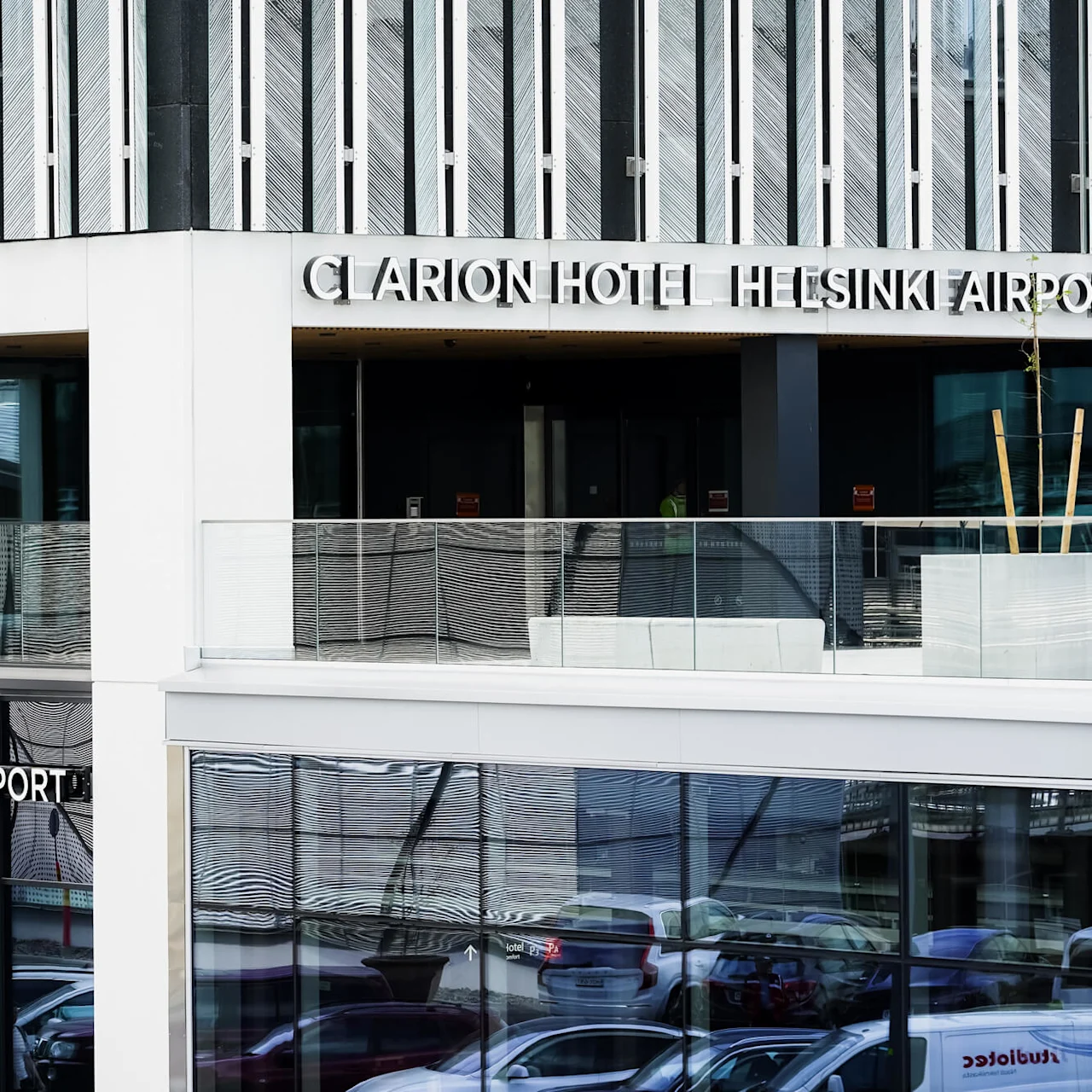Clarion Hotel Helsinki Airport building features modern glass façade; upper terrace includes seating. Text: "CLARION HOTEL HELSINKI AIRPORT" displayed prominently on building.