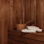 A cozy sauna interior with wooden walls and benches, featuring a bucket, ladle, and fresh white towels. Home Hotel Uppsala.