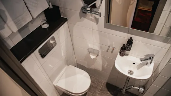 Et rent og moderne bad med toalett, vask og speil, med friske håndklær og toalettartikler.