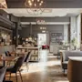 Et elegant restaurant- eller barinteriør med tregulv, varierte sitteplasser og en velutstyrt bar. Et skilt leser BAR.