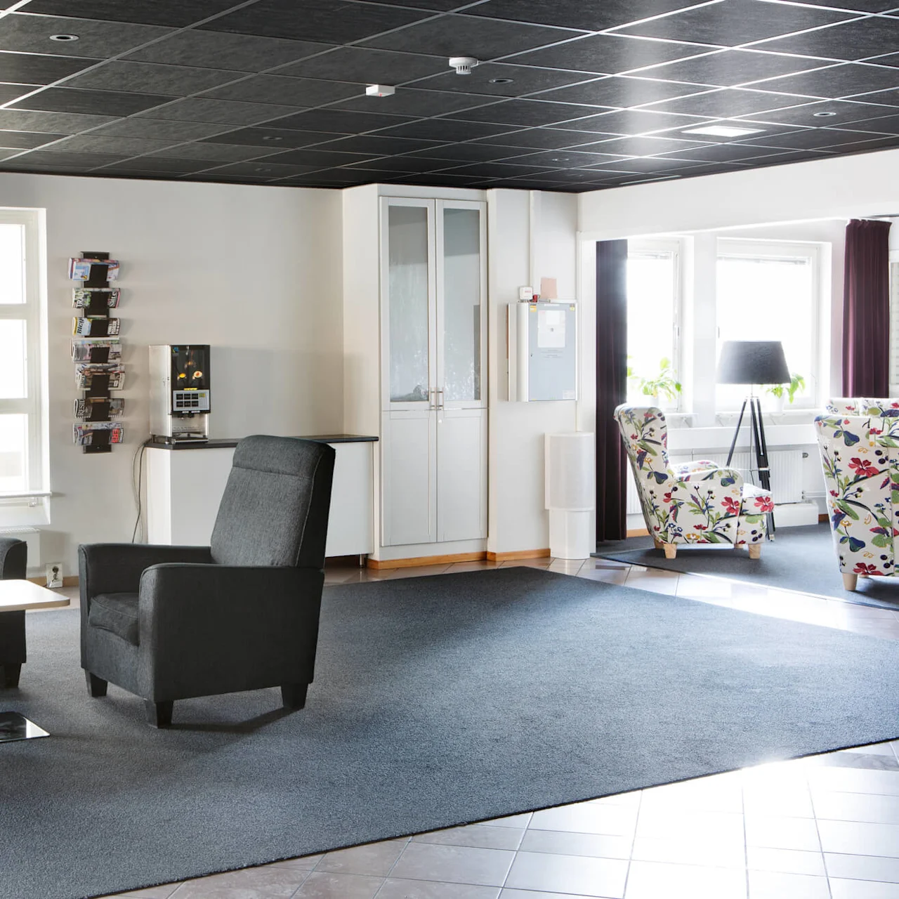 A well-lit waiting area with comfortable chairs and a coffee machine, conveying a professional yet cozy ambiance.