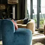 Koselig lounge med moderne sitteplasser og store vinduer med utsikt over et naturskjønt grønt landskap.