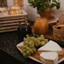 A delightful self-service food station with cheese, green grapes, fruit jams, and various crackers, ready for enjoyment.