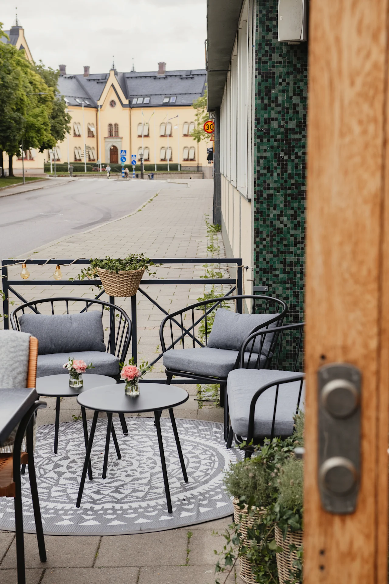 An inviting outdoor patio with comfortable seating and small tables, perfect for relaxation, next to a street with a 30 sign.