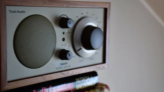 Närbild på en radio i retrostil med träram, en cirkulär högtalare och inställningsrattar. Texten lyder Bluetooth och MODEL ONE M.