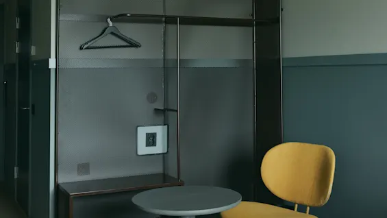 Ett modernt hotellrum på Stopover Hotel Falkenberg, utformat för en bekväm vistelse med en funktionell förvaringsenhet och sittplats.
