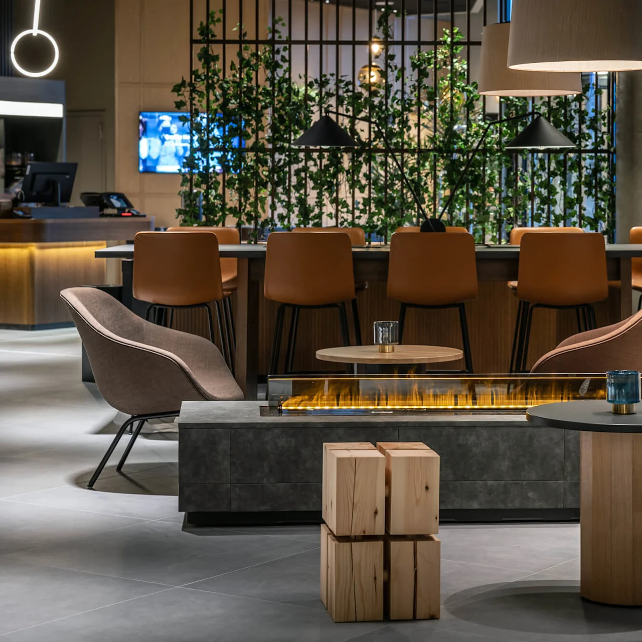 Luksuriøs lounge med moderne lænestole omkring et lavt pejsbord. I baggrunden fylder barstole en disk, med grønt og hængelamper, der forbedrer den varme atmosfære.