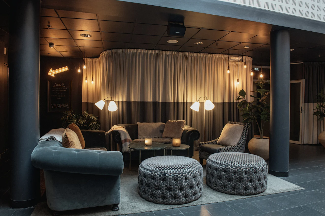 Et hyggeligt hotelloungeområde med komfortable siddepladser, varm belysning og et skilt, der peger mod Middag. Velkommen.