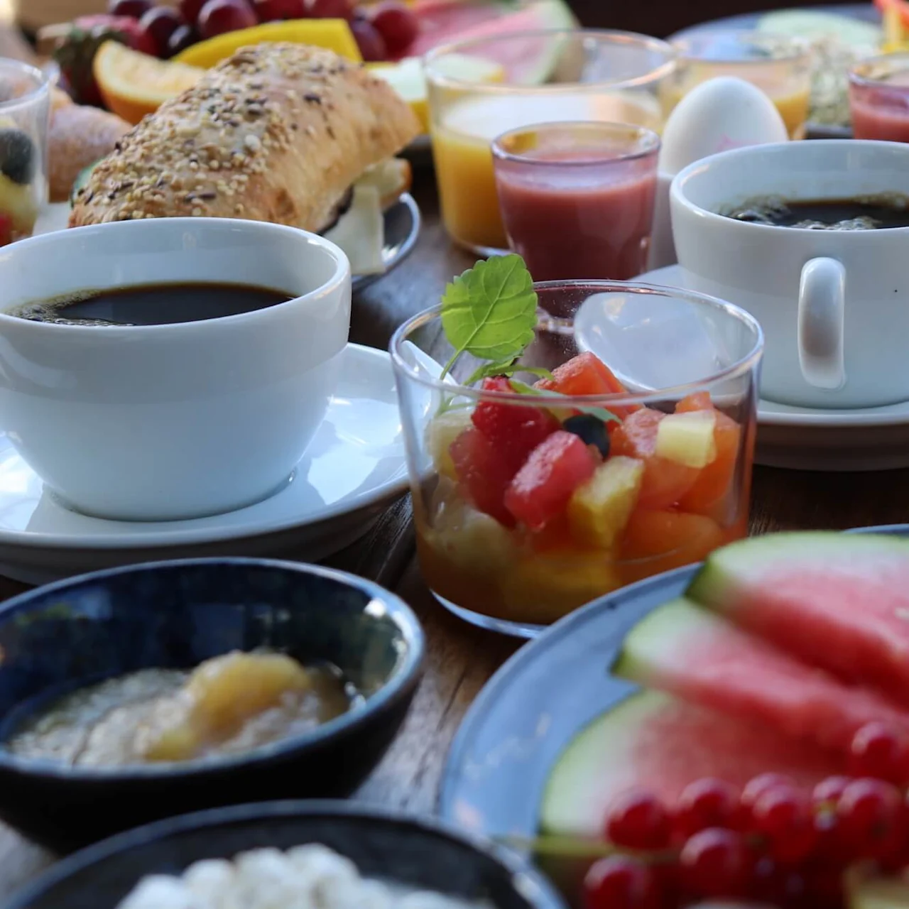 Ett urval av frukostmat och drycker presenteras på ett bord som antyder en gemensam måltid.