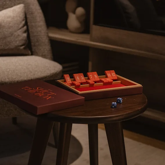Shut the Box -peli noppien kanssa puupöydällä viihtyisässä, hämärästi valaistussa huoneessa, valmiina peliin.