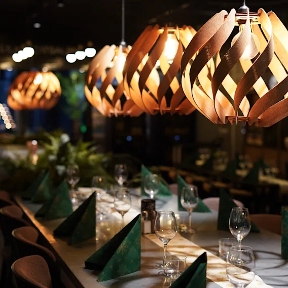 Ett elegant dukat matbord i en restaurang, upplyst av unika taklampor i trä, redo för gäster.