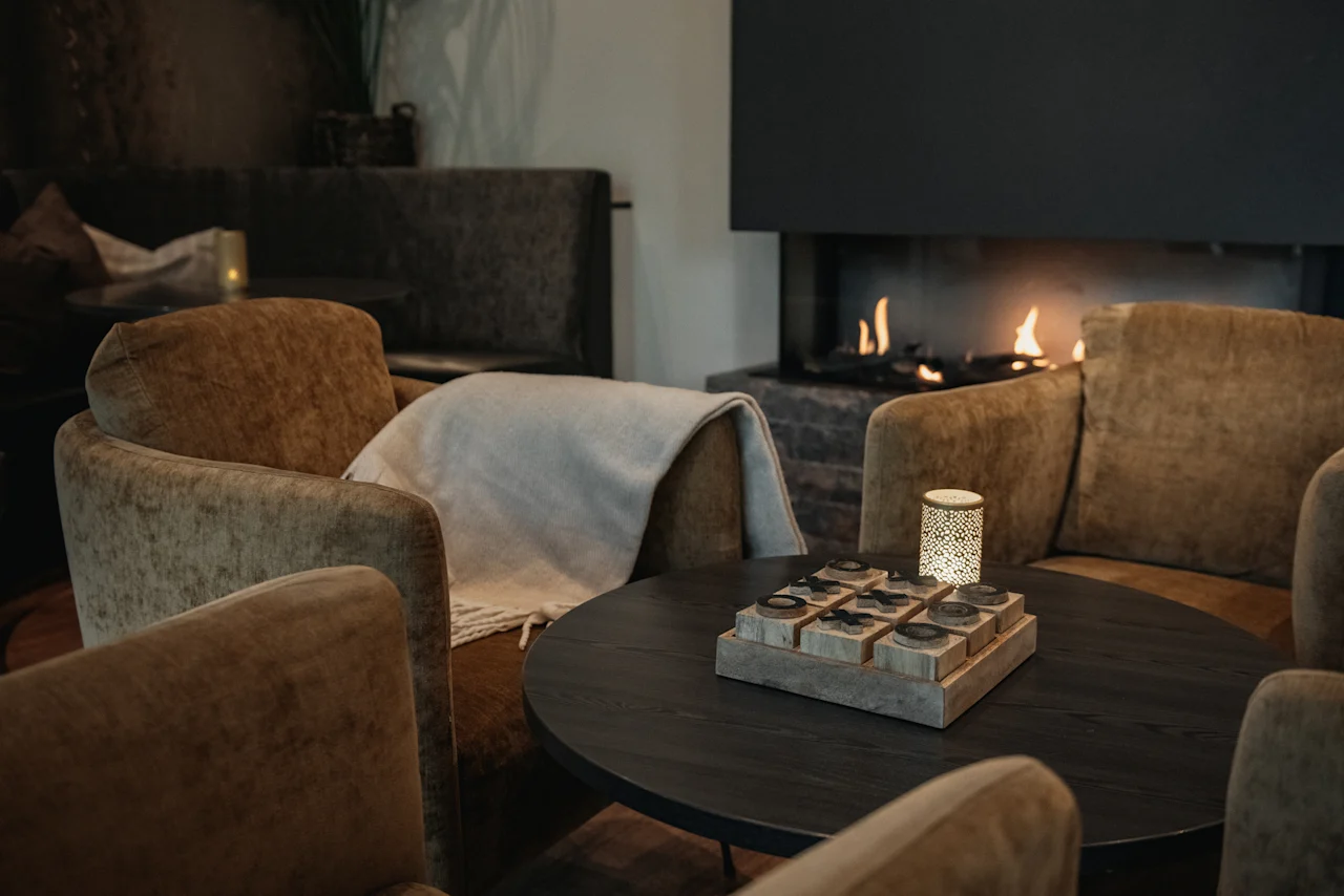 Et hyggeligt loungeområde på Home Hotel Norre Park i Halmstad med komfortable lænestole, et rundt bord og en varm pejs.