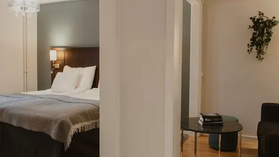 A cozy hotel room at Home Hotel Kung Oscar with a bed on one side and a small lounge area on the other.