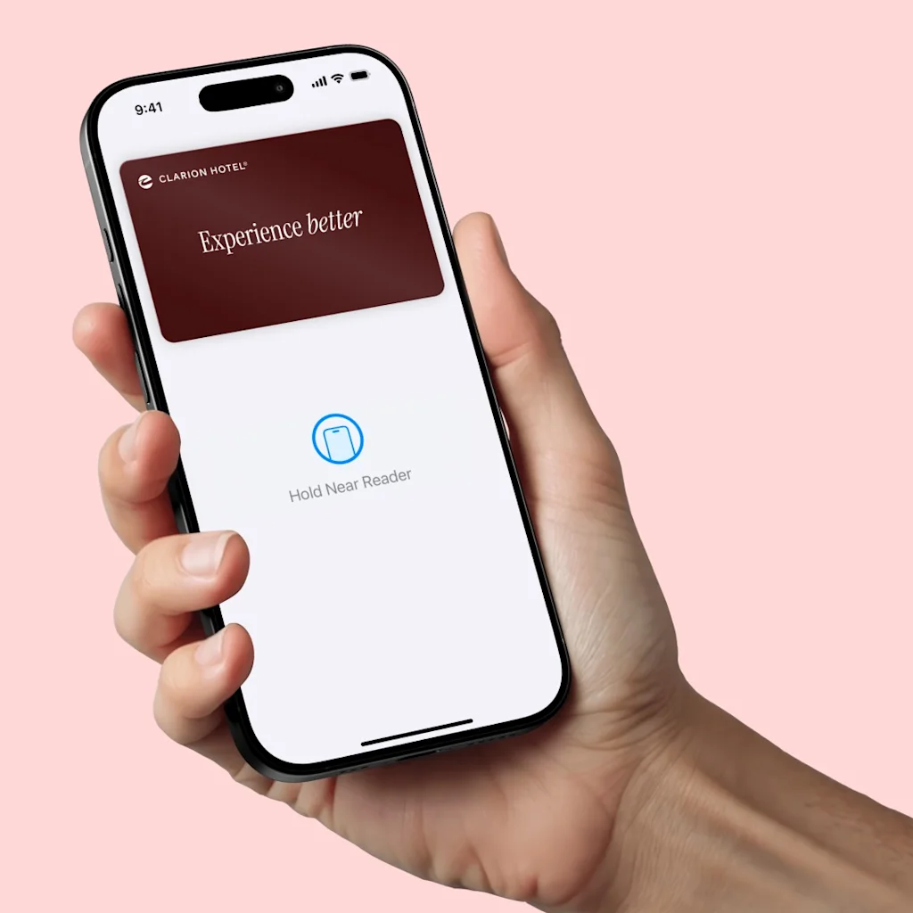 Hånd der holder en mobil med teksten Experience better og et Strawberry hotelkort i Apple Wallet