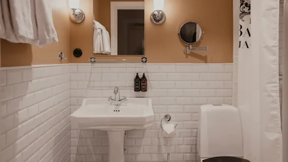 Home Hotel Baltzar - Superior Room: A clean and elegant bathroom with white subway tiles, a pedestal sink, and warm lighting.