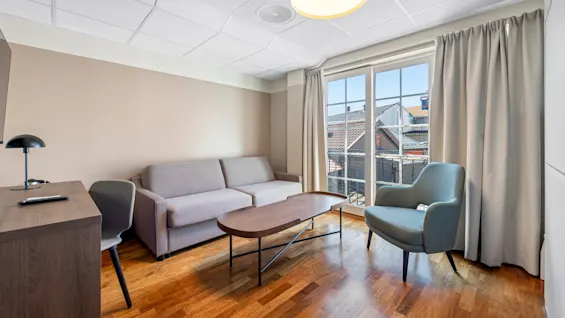 Modern living room with furniture, sunny day through balcony doors, no text.
