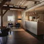 Et stilfuldt og indbydende hotelreceptionsområde med en moderne disk, komfortable siddepladser og rustikke synlige træbjælker.