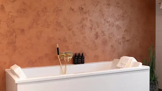 A welcoming bathroom at Home Hotel Grand Bodø, showcasing a clean white bathtub with stylish golden taps and bath products.
