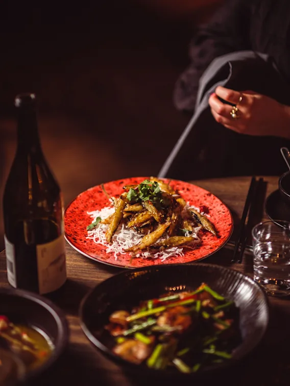 En person som njuter av en måltid på en restaurang, med olika rätter och drycker på ett träbord.