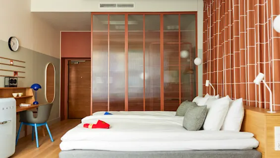 Modern hotel room with twin beds a small desk and warm terracotta accents