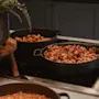 Et nærbilde av en frokostbuffé med sprøtt bacon, pølser og en plante i en dekorativ potte.