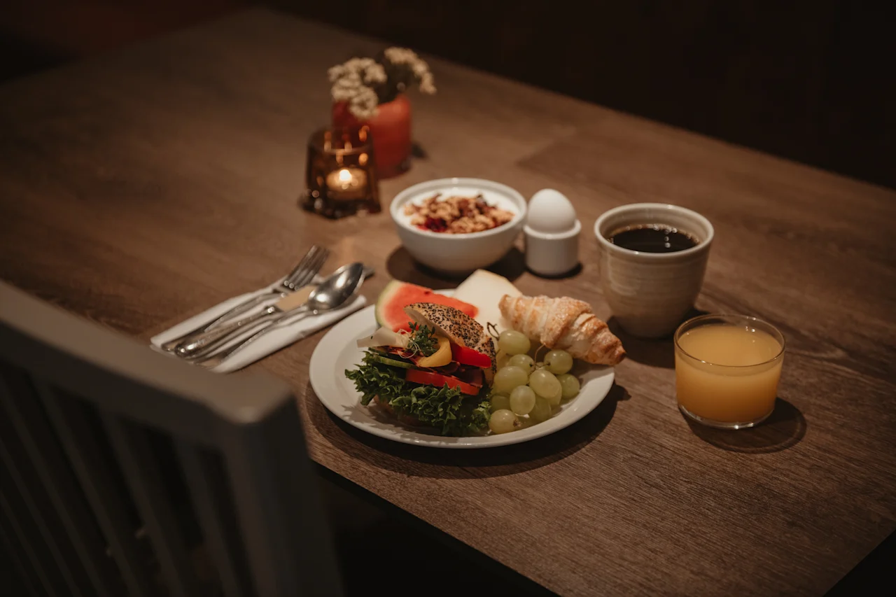 En varm og innbydende frokostdekning på et trebord, med en tallerken med fersk mat, frokostblanding, kaffe og juice.