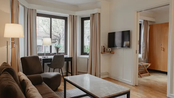 Et komfortabelt opholdsområde på Home Hotel Norre Park i Halmstad, med sofa, skrivebord og vægmonteret TV.