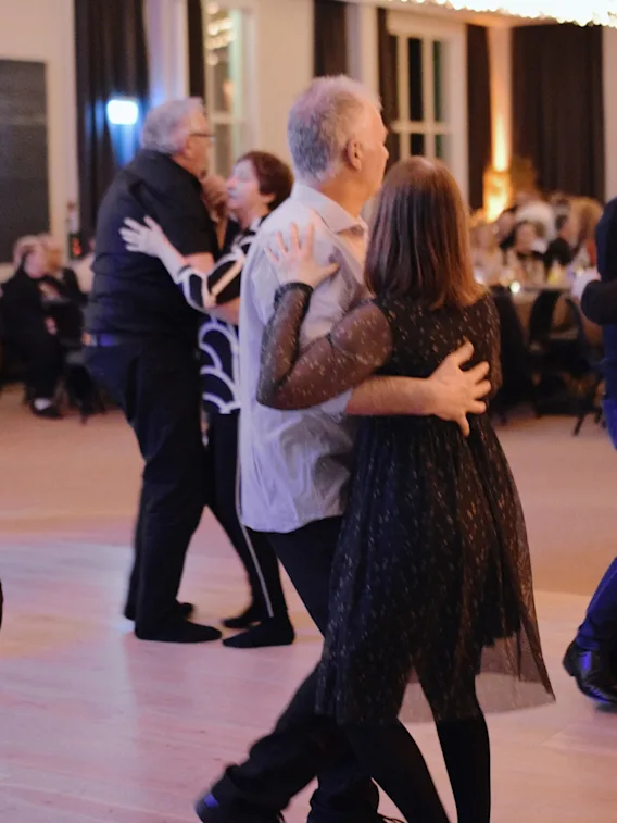 Folk danser i par på et arrangement og nyter musikken og selskapet i en varm, innbydende atmosfære.
