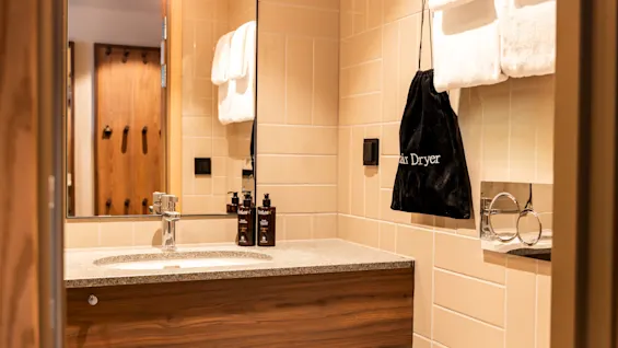 Bathroom vanity at Quality Hotel The Book in Gothenburg with a sink, mirror, toiletries, towels, and a bag labeled Hair Dryer.