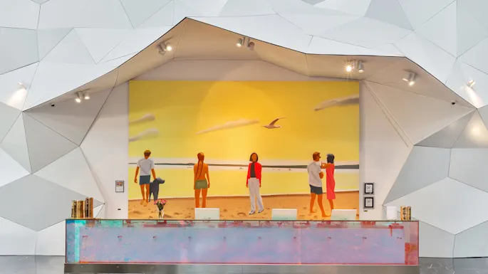 Vastaanottotiski koristeltu abstraktilla taiteella, vastapäätä seinämaalausta esittäen rantaa auringonlaskussa. Ihmiset rannalla, modernin, kulmaisen seinämuotoilun ympäröimänä.