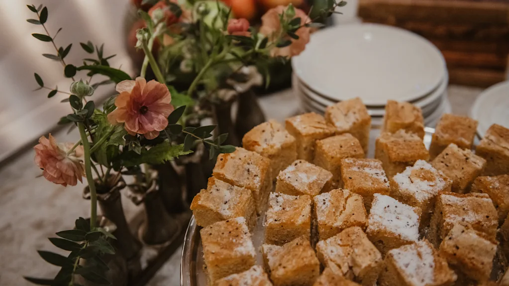 A delightful spread of square cakes, some dusted with sugar, alongside floral arrangements at Home Hotel Baltzar.