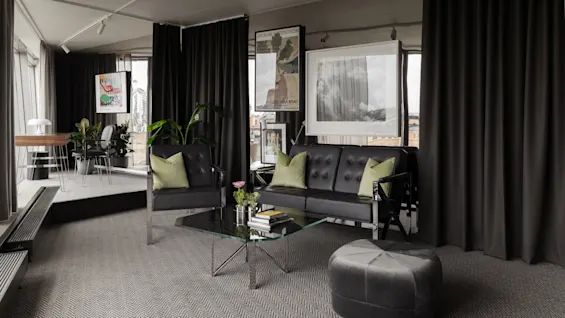 Stratum Suite Clarion Hotel Signissä Tukholmassa. Moderni oleskelutila mustilla huonekaluilla, lasipöydällä ja taiteella. Teksti: STOCKHOLM, GALLERIA MYNT.