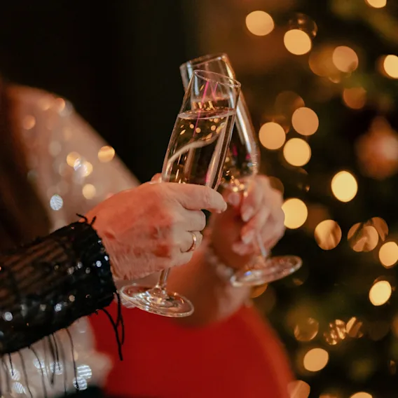 To personer som skåler med champagneglass i festlig belysning.