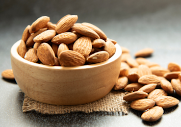 A ceramic bowl filled with raw almonds on burlap fabric, on that note, can dogs have almonds?