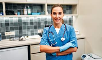 A confident veterinarian in blue scrubs and latex gloves stands with arms crossed in a well-equipped exam room, stethoscope around her neck. Understanding veterinary terminology can make a real difference when discussing your pet's health with a professional. From basic veterinary terminology like "prognosis" and "auscultation" to more complex veterinary medical terminology used in diagnoses and treatment plans, knowing common vet words helps pet owners ask better questions and make more informed decisions. 
