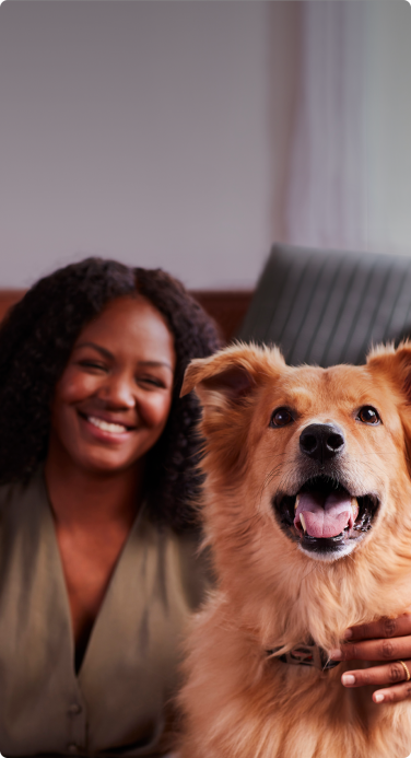 African-American woman smiling at dog with pet insurance