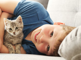 little-boy-holding-kitten-on-couch