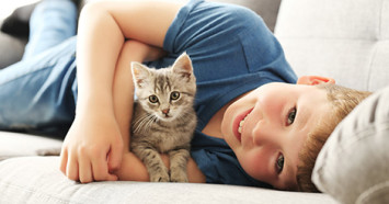 little-boy-holding-kitten-on-couch