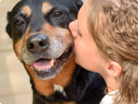 Blond woman kissing Rottweiler dog