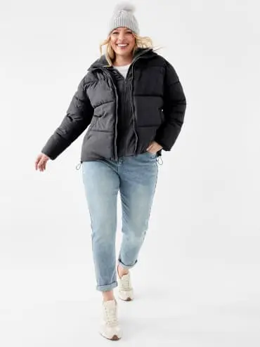 woman wearing blue jeans and a black puffer jacket with a be