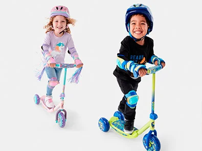 a little boy and girl riding a pink and green scooter each