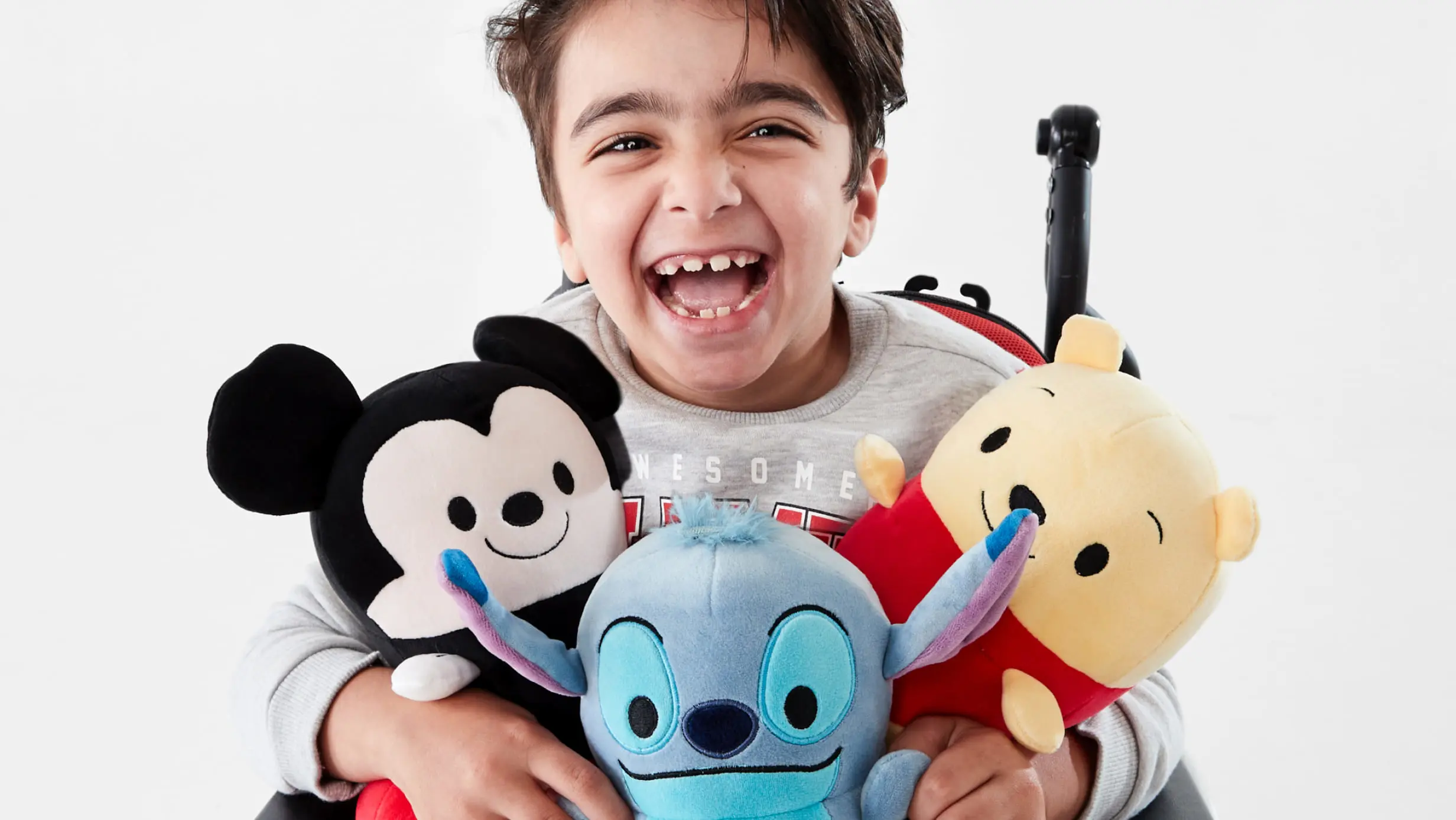 a little boy hugging an assortment of Disney plush toys